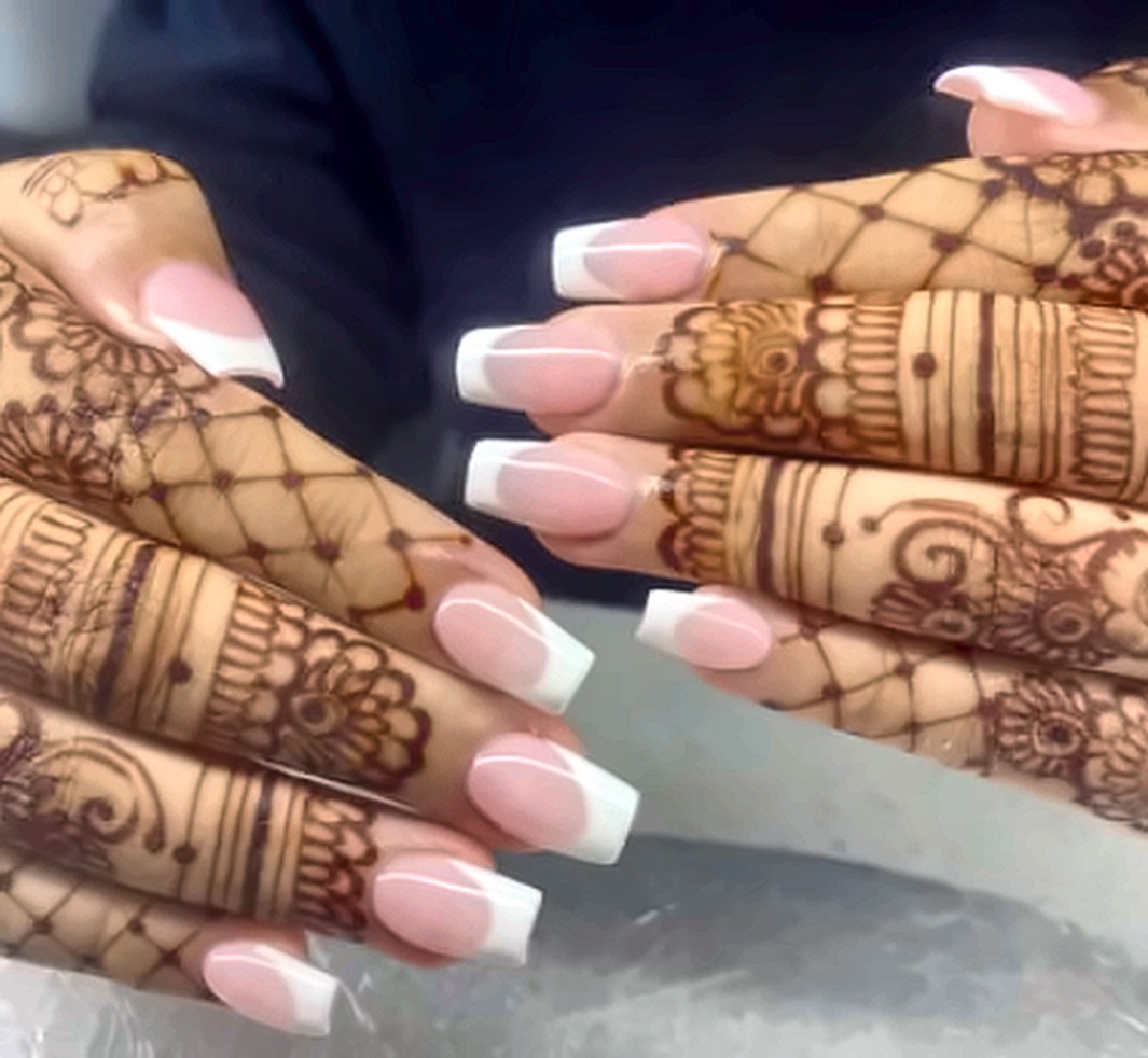 Classic white French tips on hands decorated with henna