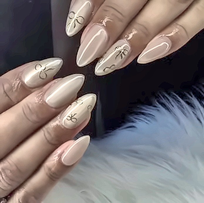 Nude almond nails with gold bow art